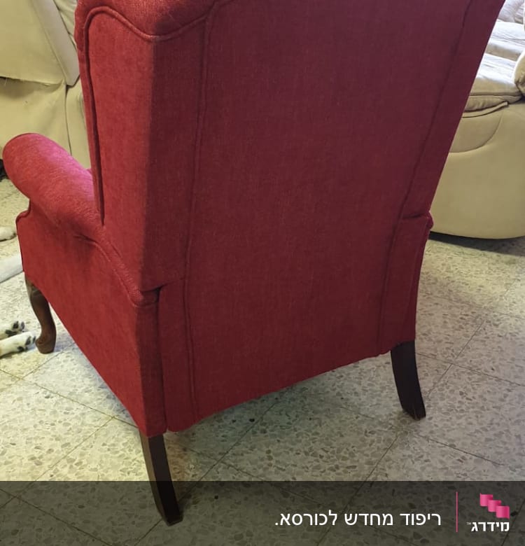 כורסה מרופדת באדום עם רגלי עץ כהות